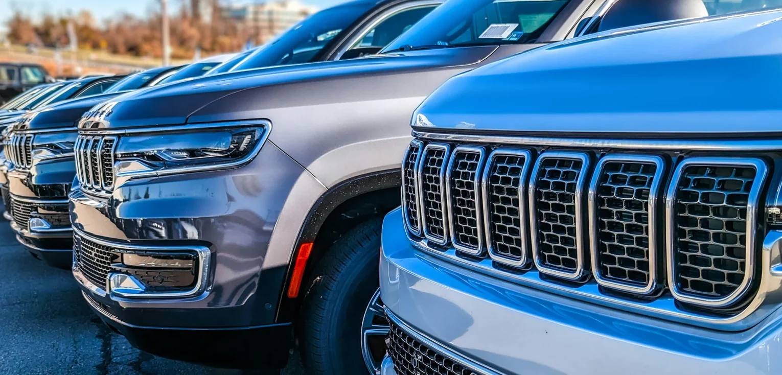 The front bumpers of several used cars parked in a line.