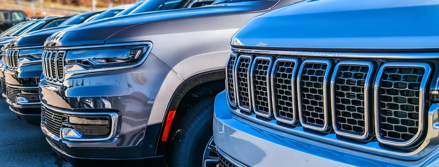 The front bumpers of several used cars parked in a line.