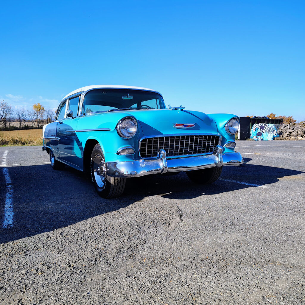 A light blue classic car in Restored Auto's parking lot