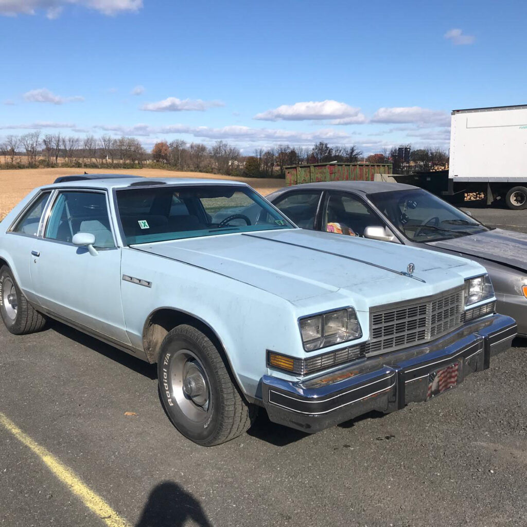 A light blue vintage car in Restored Auto's parking lot