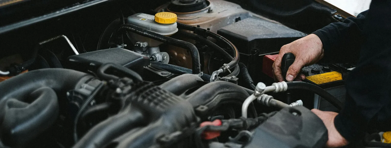 A mechanic looking performing maintenance under the hood of a car