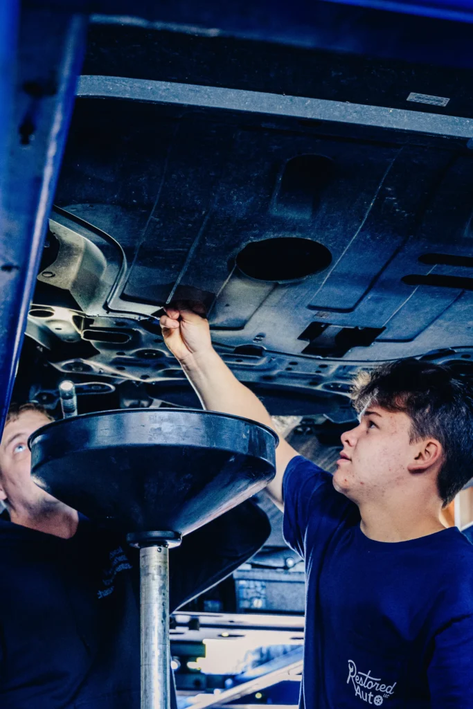 A Restored Auto staff member performing an oil change