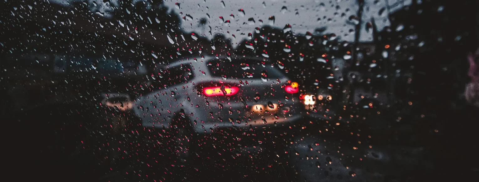 A car's taillights through a rainy window