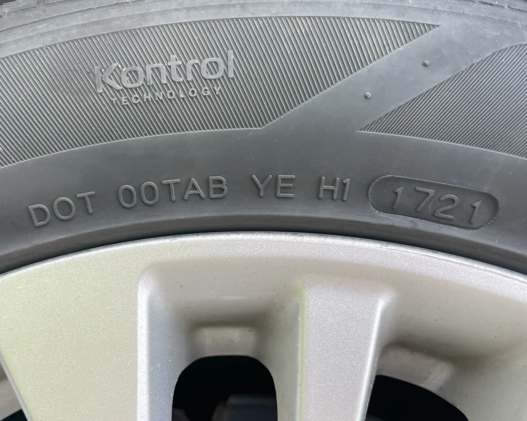 A photo of a tire with a DOT designation that says "DOT 00TAB YE H1 1721"