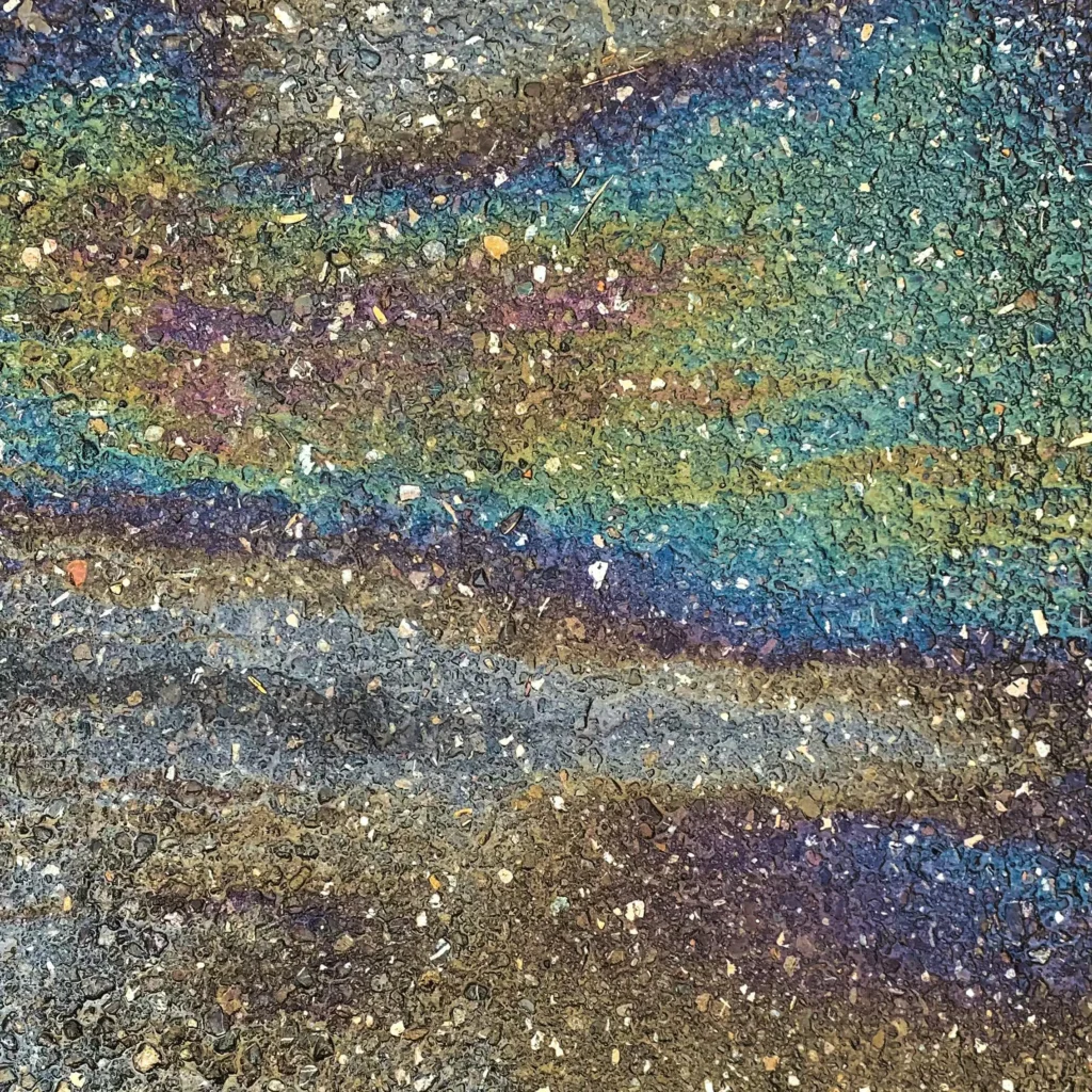 The rainbow sheen of oil on pavement